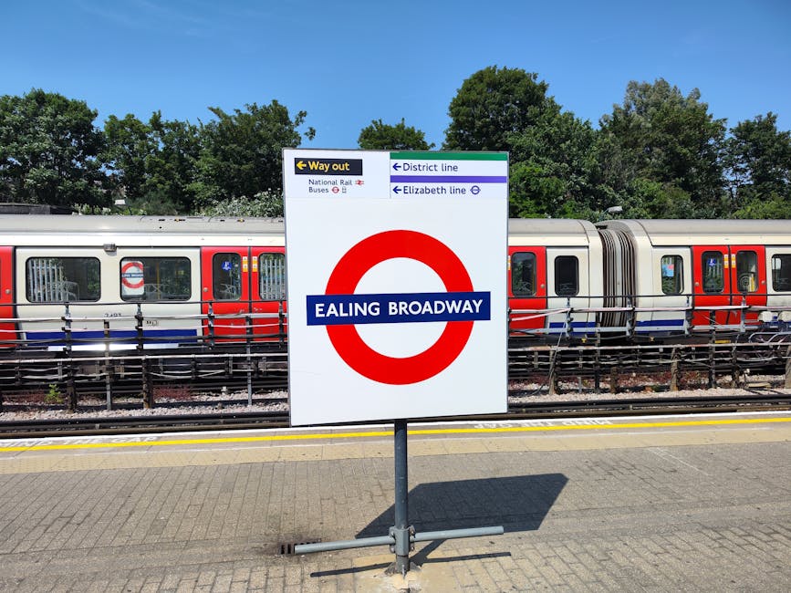 Underground railway station platform at Belsize Park, featuring curved white tiled walls with the London Underground roundel sign and a modern advertising panel. The tiled platform floor displays a ge